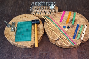 かんたん革細工体験で使用するゴムハンマーや刻印、革紐、きらきらストーンなどの道具と素材一式。