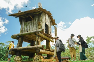 ビオスの丘の周遊型謎解きで、園内の木造展望台の前に集まり、次の手がかりを確認しながら進行する参加者